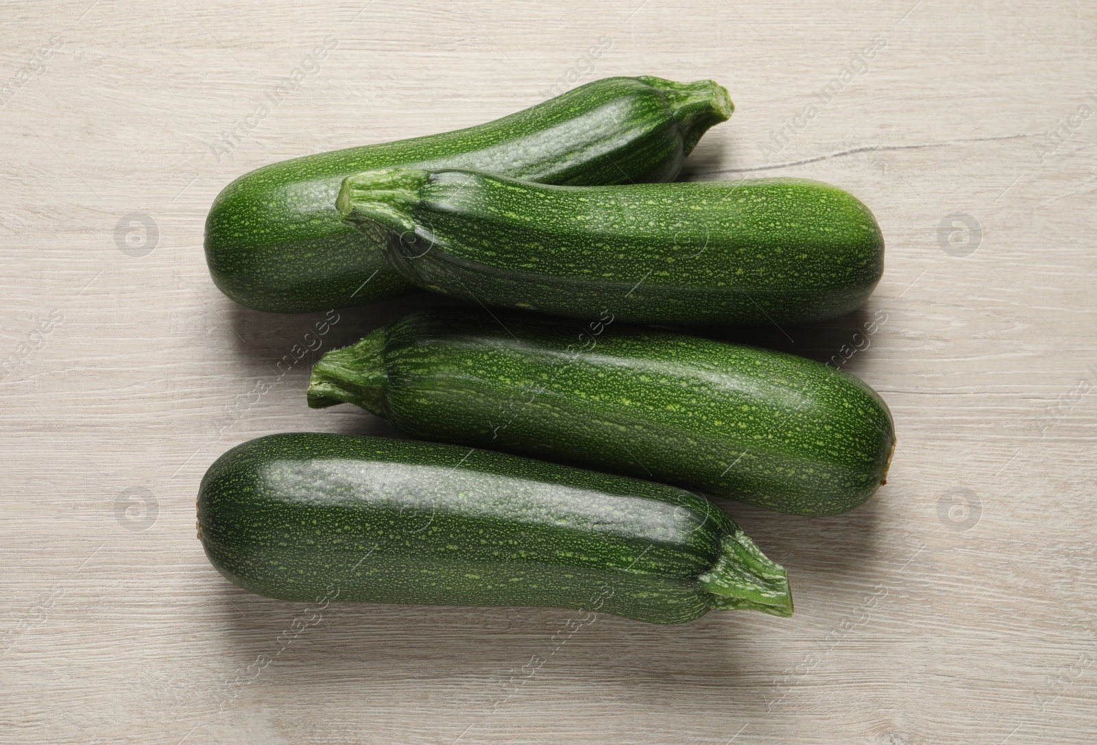 Photo of Raw ripe zucchinis on white wooden table, flat lay