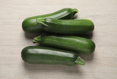 Raw ripe zucchinis on white wooden table, flat lay