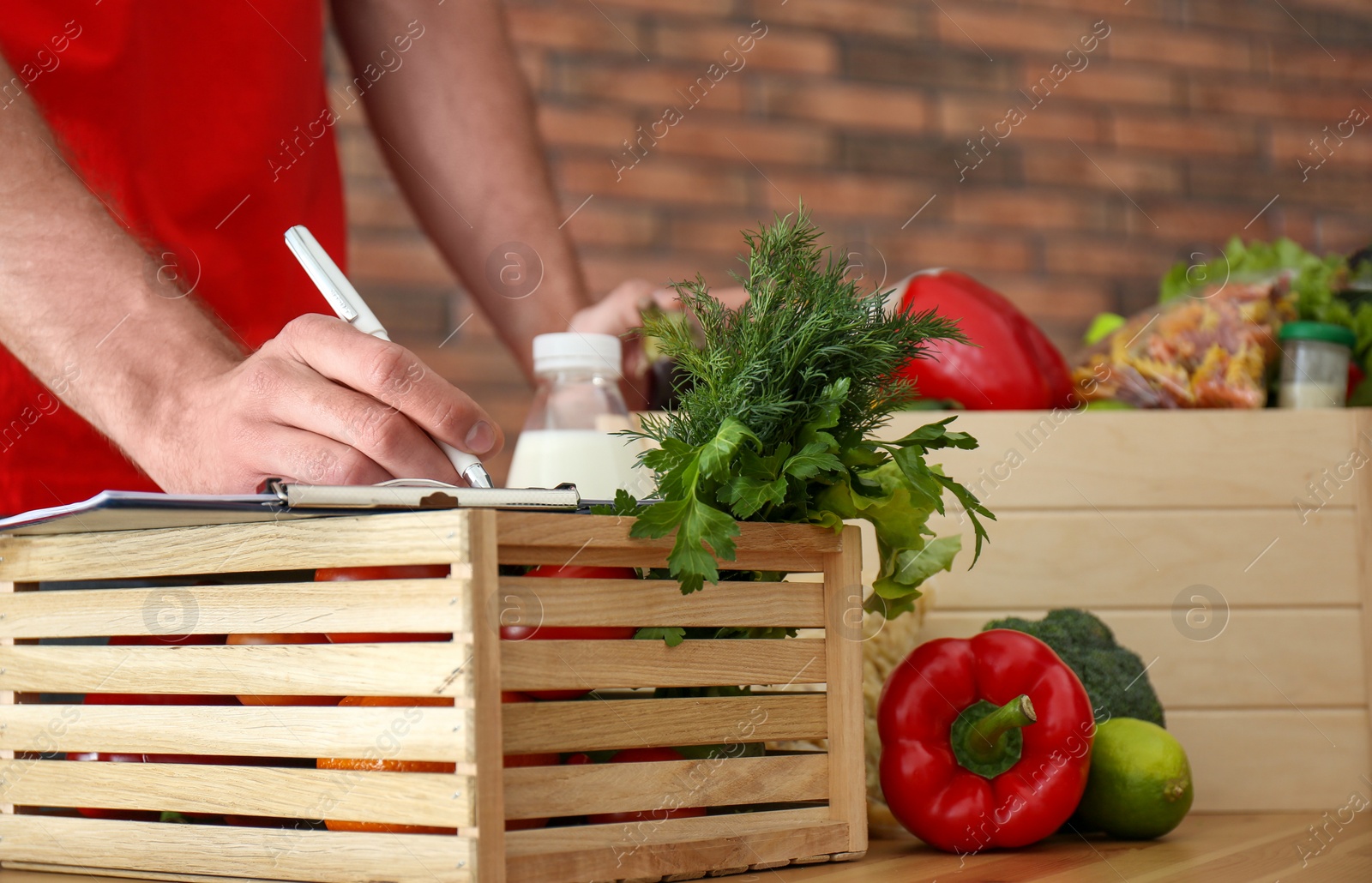 Photo of Man with fresh products at table indoors, closeup. Food delivery service