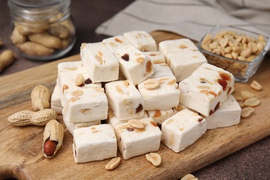 Pieces of delicious nougat and nuts on wooden board, closeup