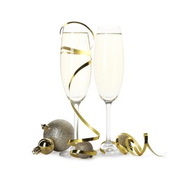 Photo of Glasses of champagne with serpentine streamers and Christmas balls on white background