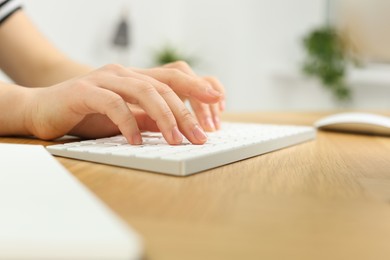 Photo of Home workplace. Woman typing on keyboard at wooden desk indoors, closeup