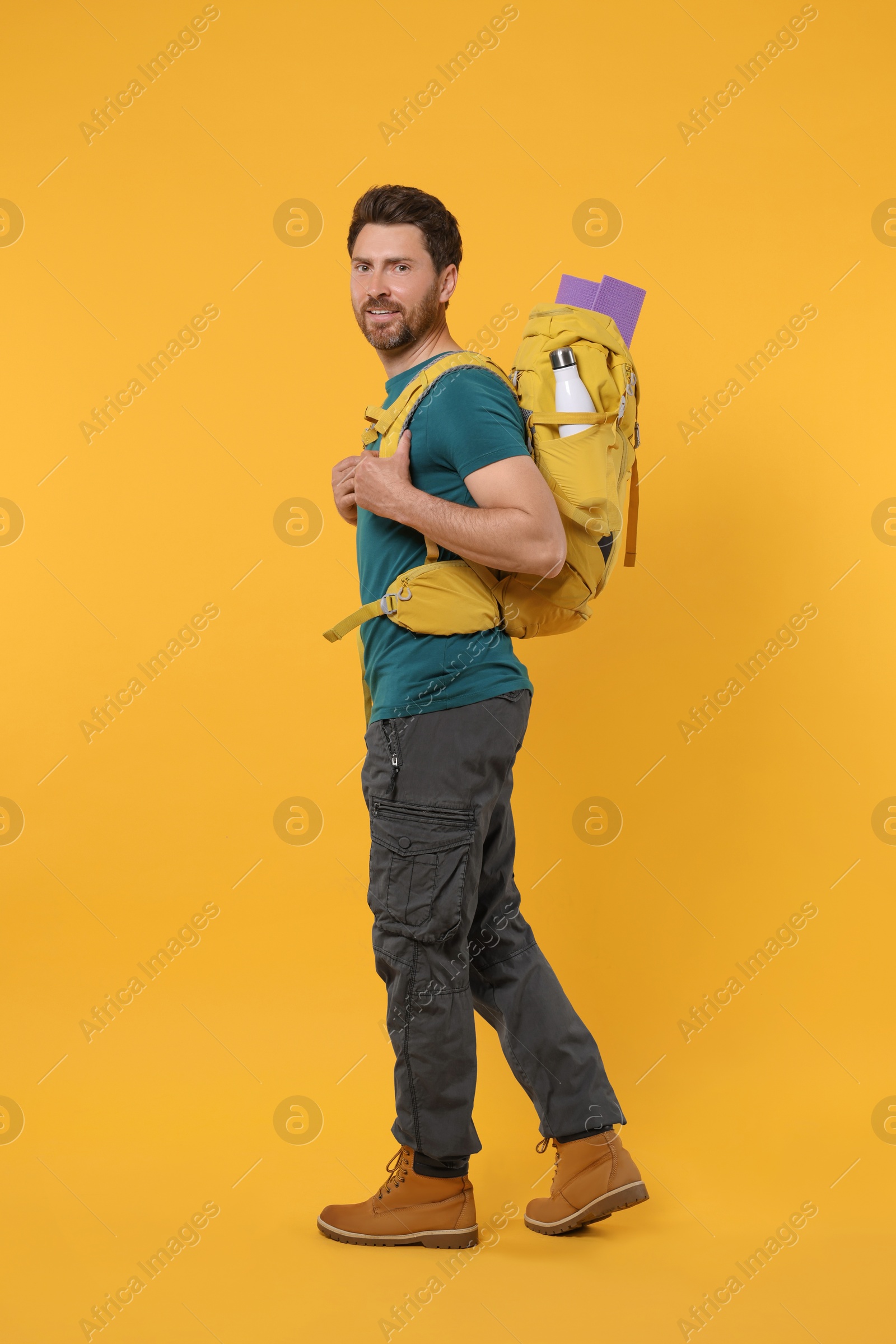 Photo of Man with backpack on orange background. Active tourism