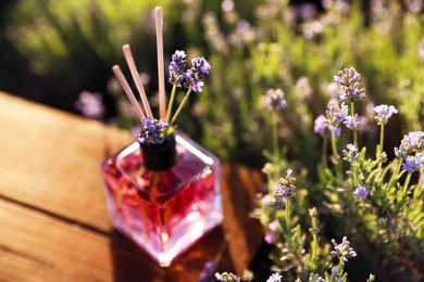 Reed air freshener on wooden table in blooming lavender field