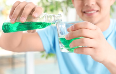 Man pouring mouthwash from bottle into glass, closeup. Teeth care