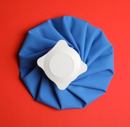 Ice pack on red background, top view