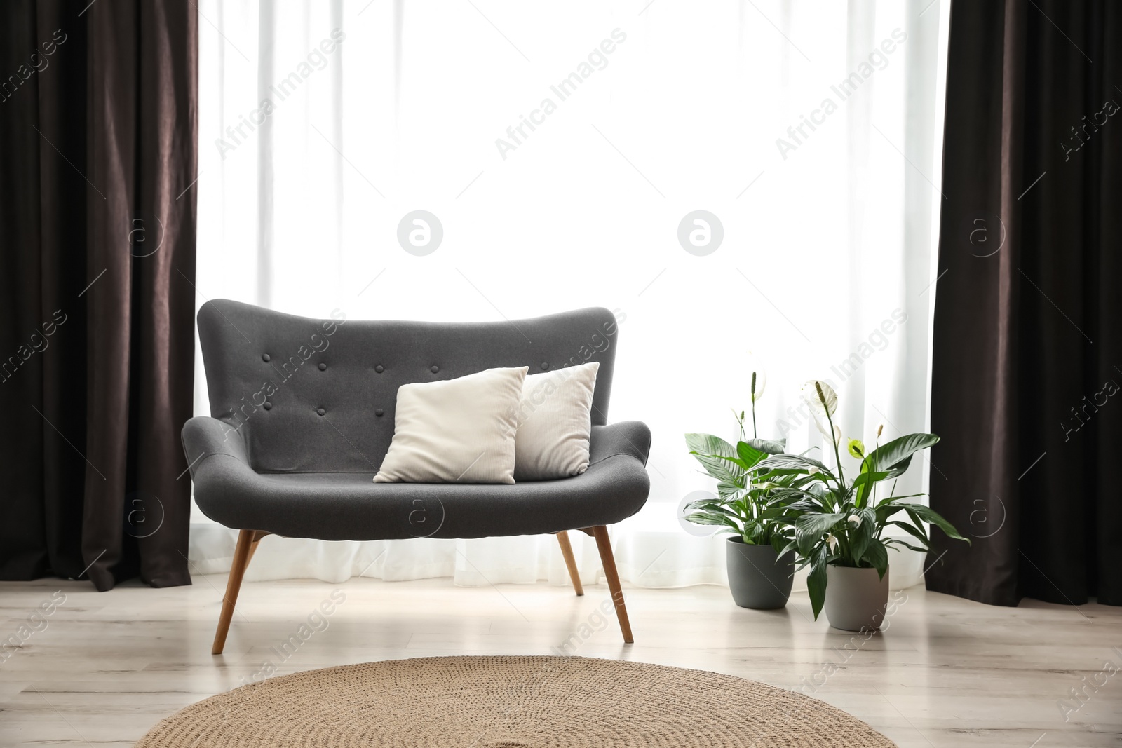 Photo of Comfortable sofa near window with elegant curtains in room