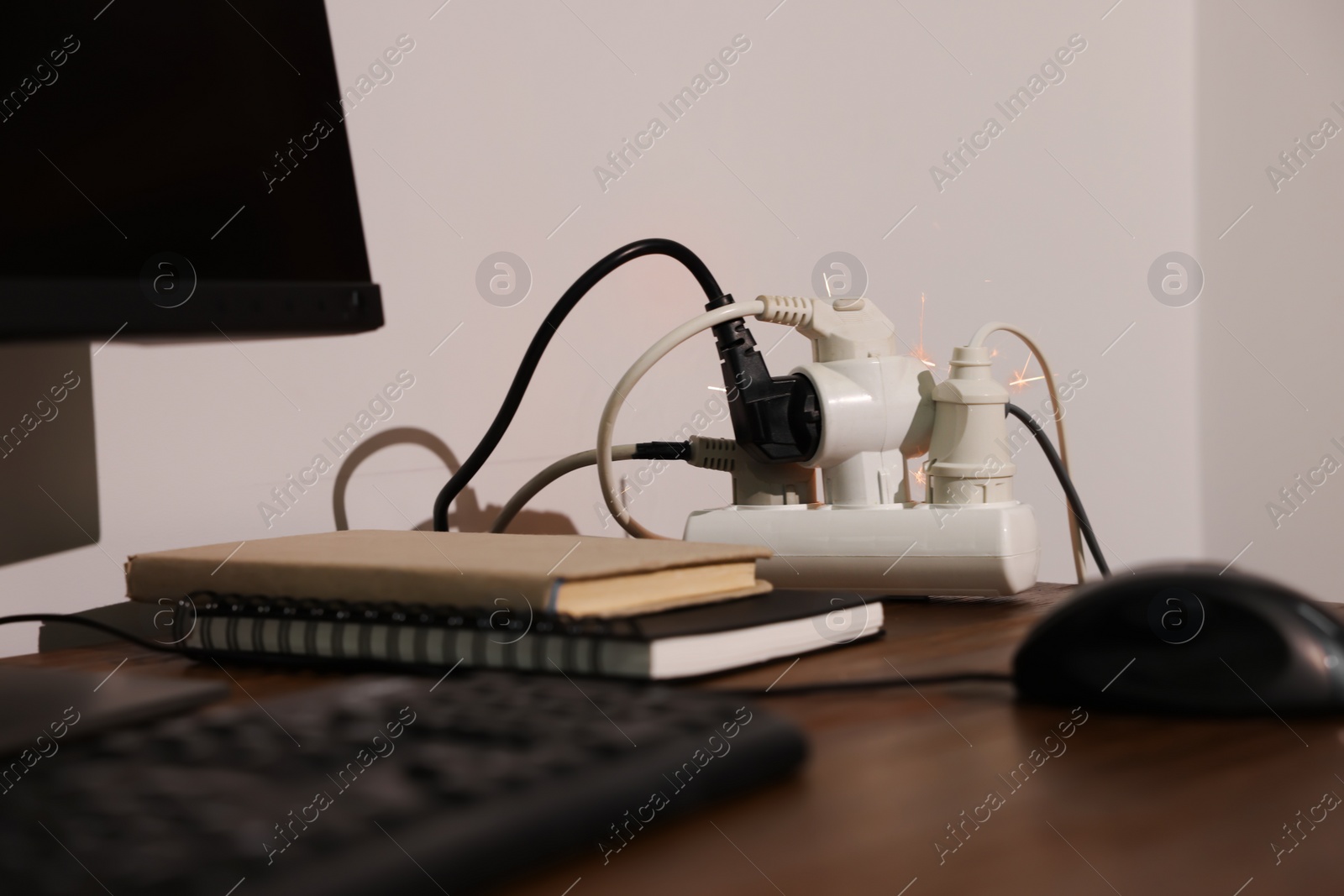 Photo of Inflamed plug in power strip indoors on wooden table. Electrical short circuit