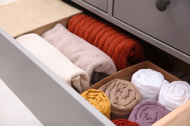 Photo of Open drawer with folded clothes indoors, closeup. Vertical storage