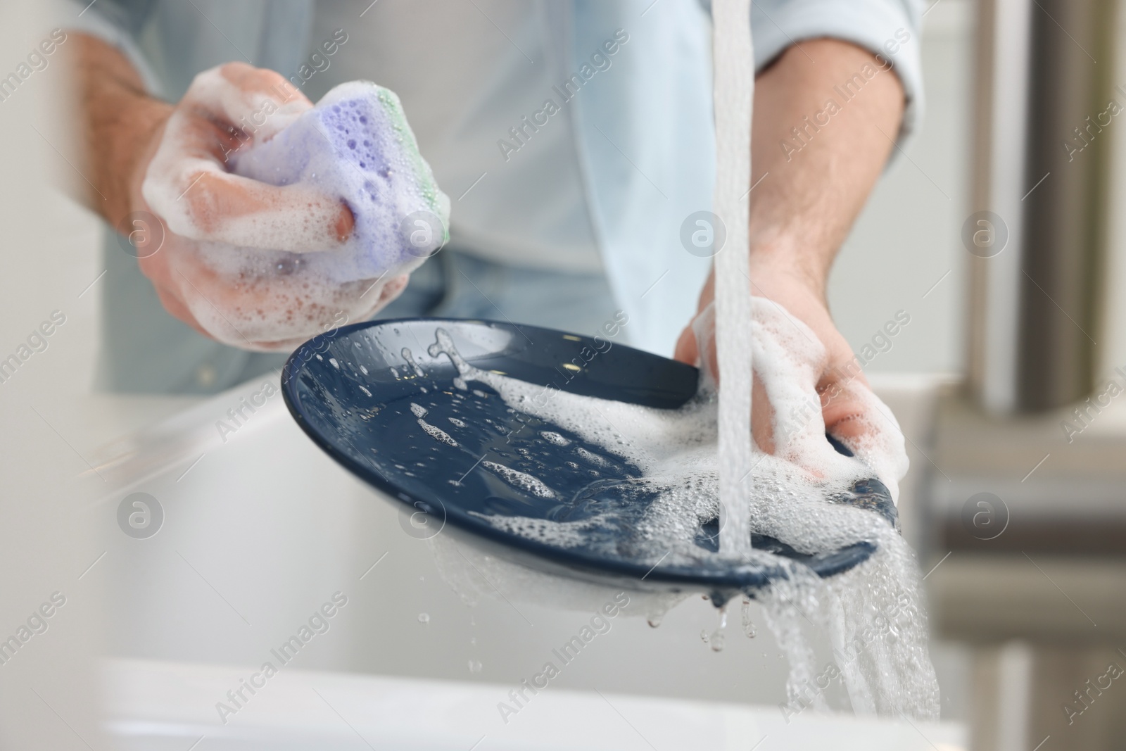 Photo of Man washing plate above sink in kitchen, closeup