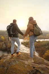 Photo of Couple of hikers with travel backpacks near mountain river, back view