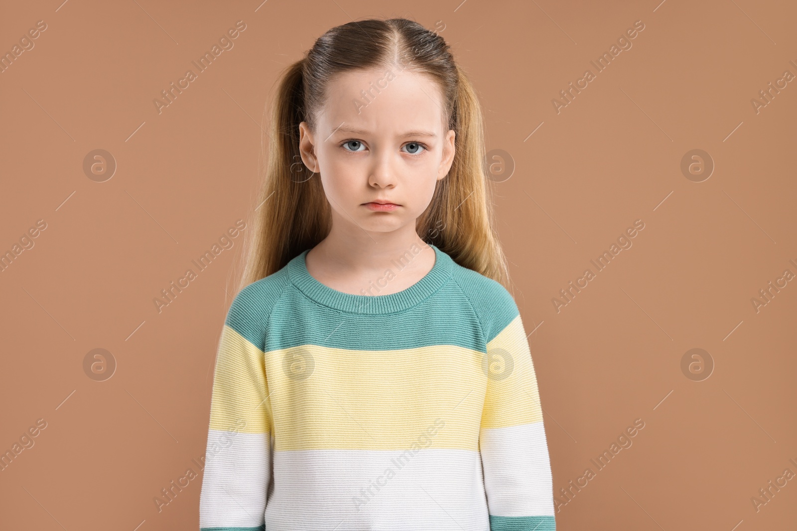 Photo of Portrait of sad girl on light brown background