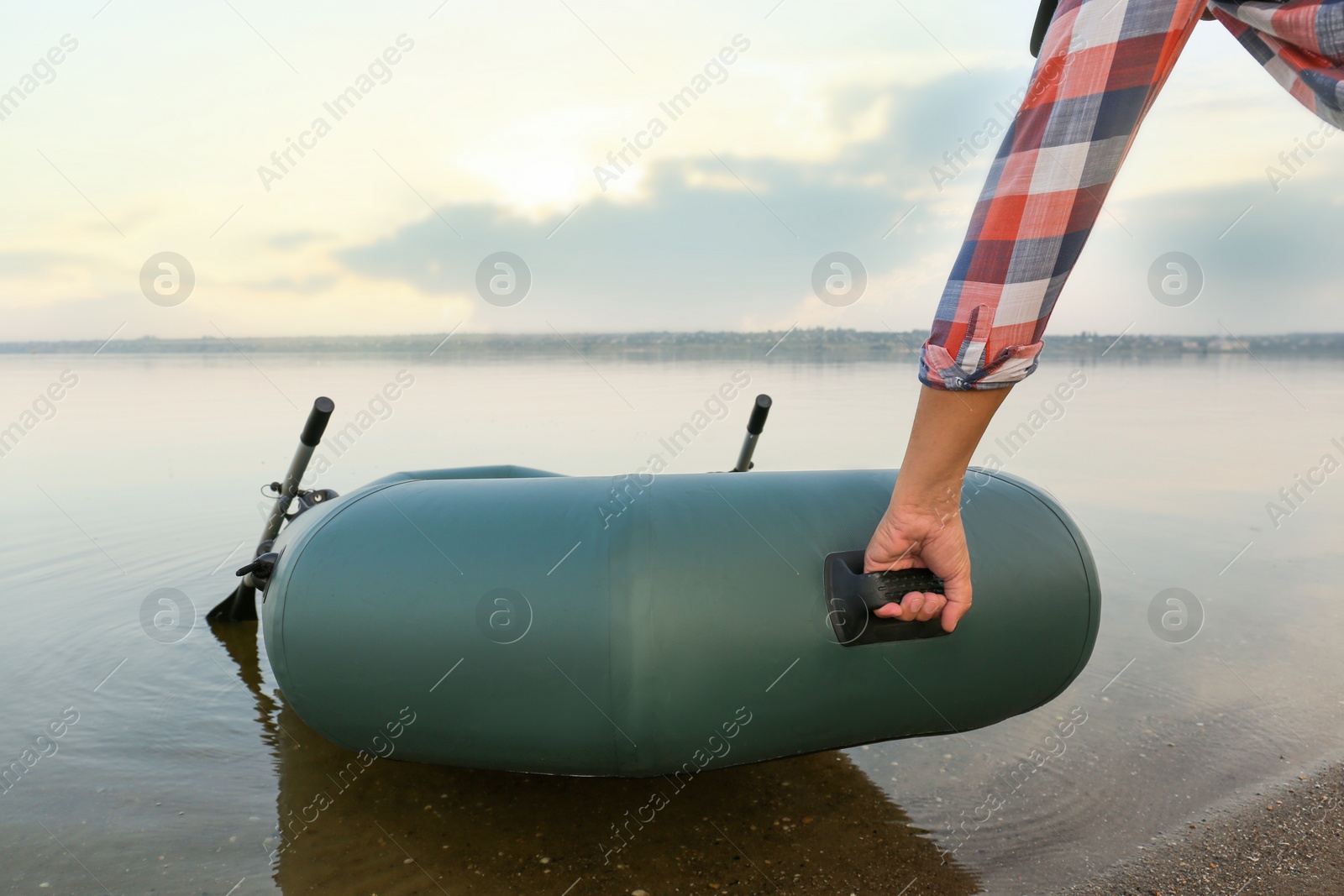 Photo of Man with inflatable rubber fishing boat at riverside, closeup