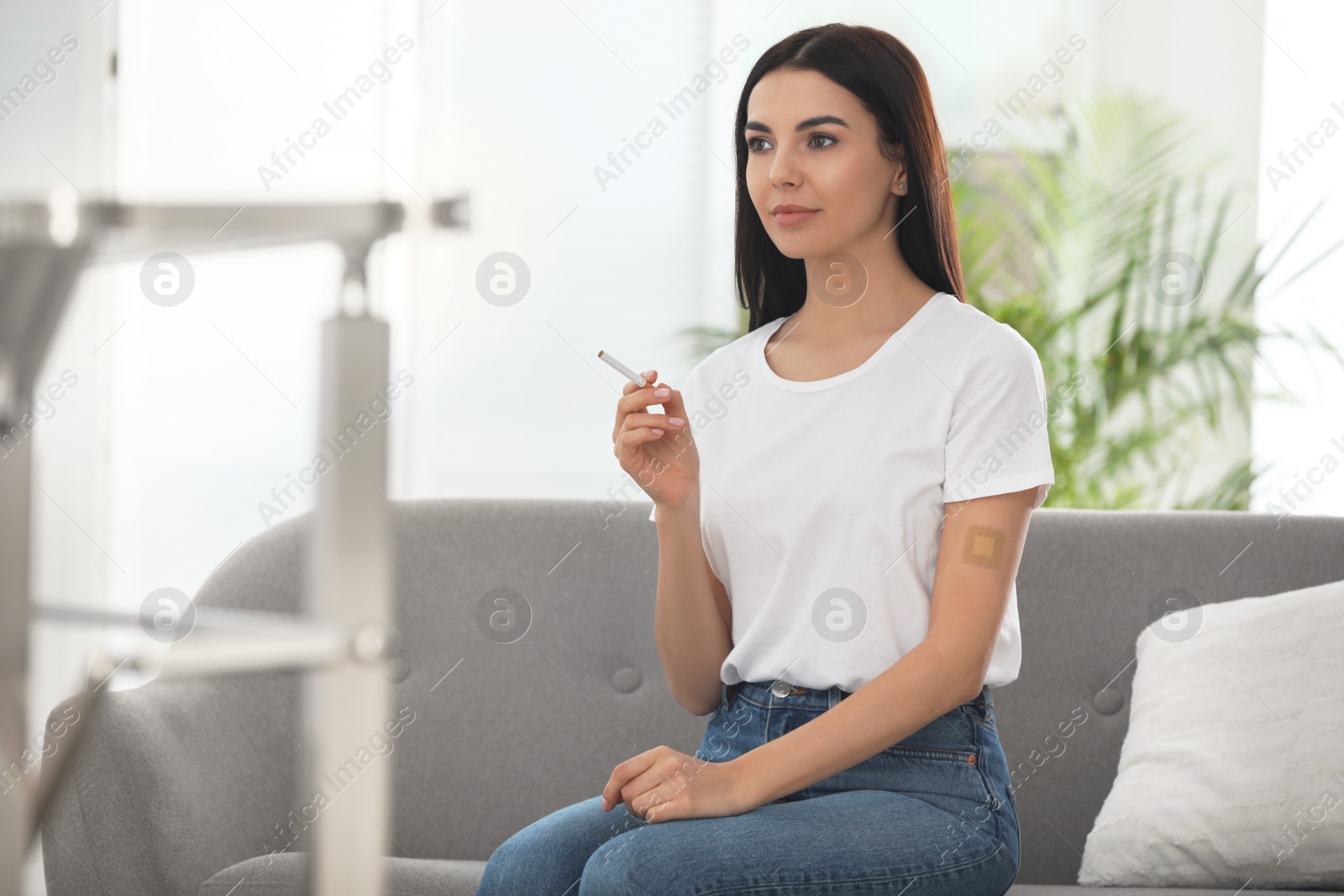 Photo of Young woman with nicotine patch and cigarette at home