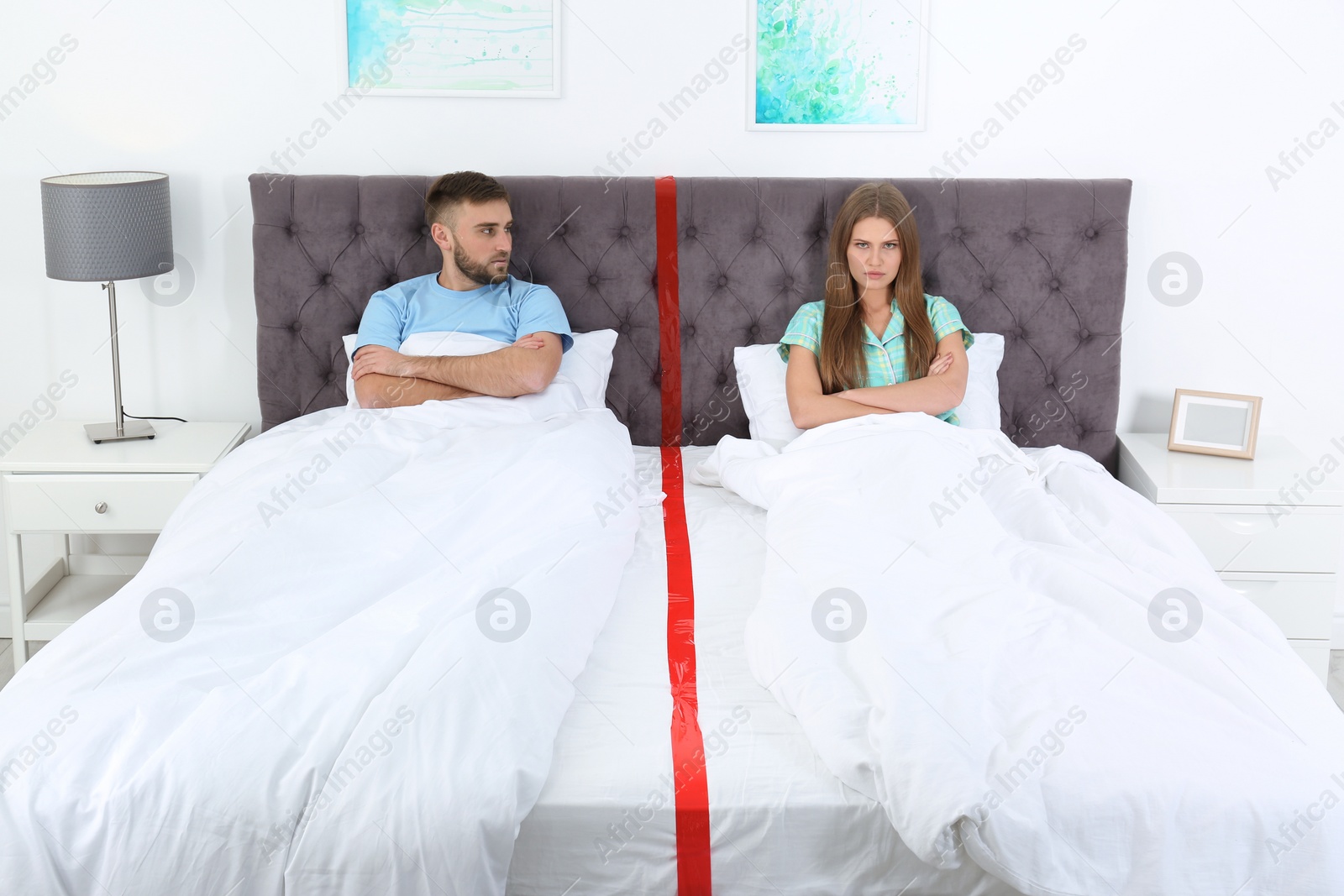 Photo of Upset couple with relationship problems lying separately in bed at home