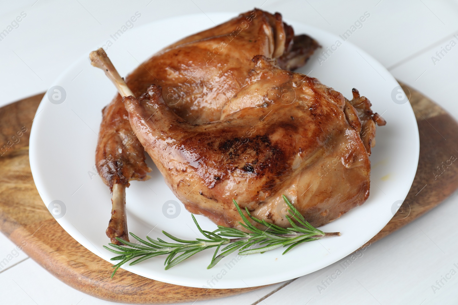 Photo of Tasty cooked rabbit meat with rosemary on white table, closeup