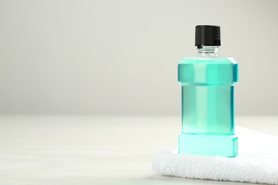 Photo of Mouthwash with towel and space for text on light background. Teeth hygiene