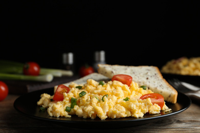 Photo of Tasty scrambled eggs with cherry tomato and bread on wooden table