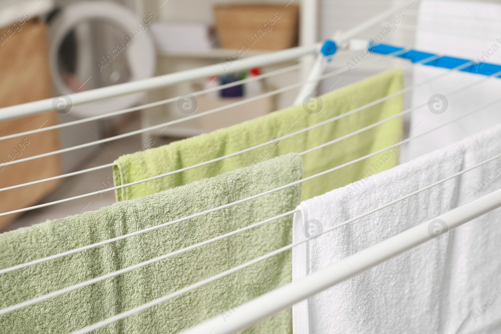 Photo of Clean terry towels hanging on drying rack indoors, closeup