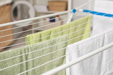 Clean terry towels hanging on drying rack indoors, closeup