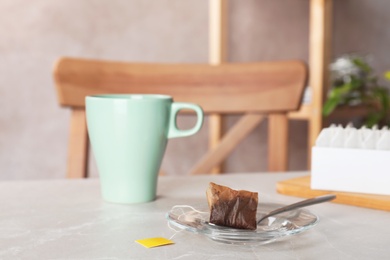 Photo of Saucer, spoon with used teabag and cup on table. Space for text