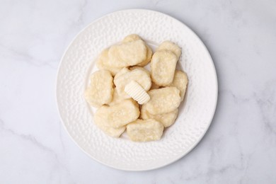 Photo of Plate of tasty lazy dumplings with butter on white marble table, top view