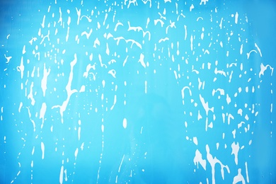 Photo of Glass covered with suds on color background