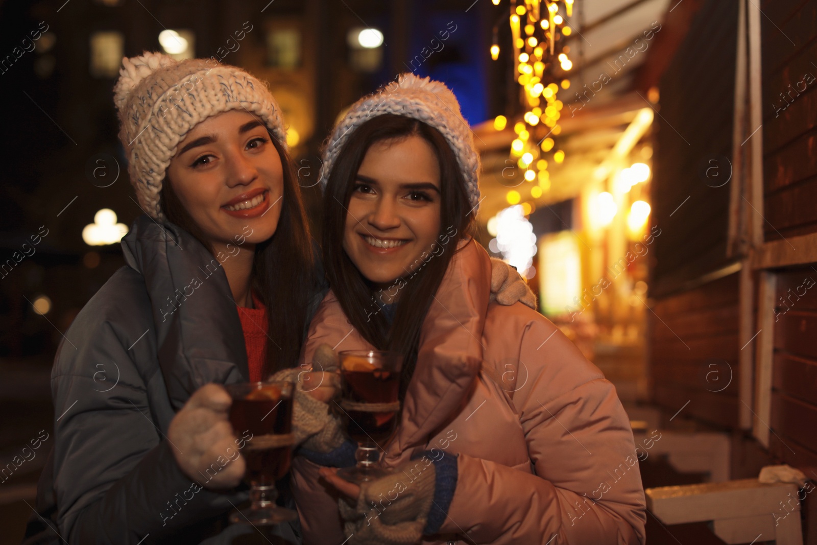 Photo of Friends with glass cups of mulled wine at winter fair
