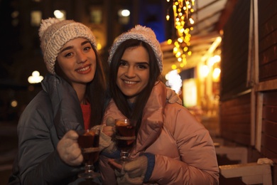 Friends with glass cups of mulled wine at winter fair