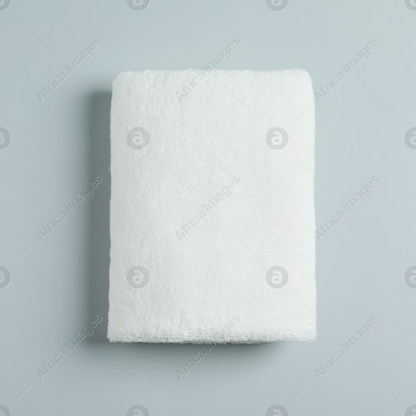 Photo of Soft folded towel on light background, top view