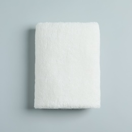 Soft folded towel on light background, top view