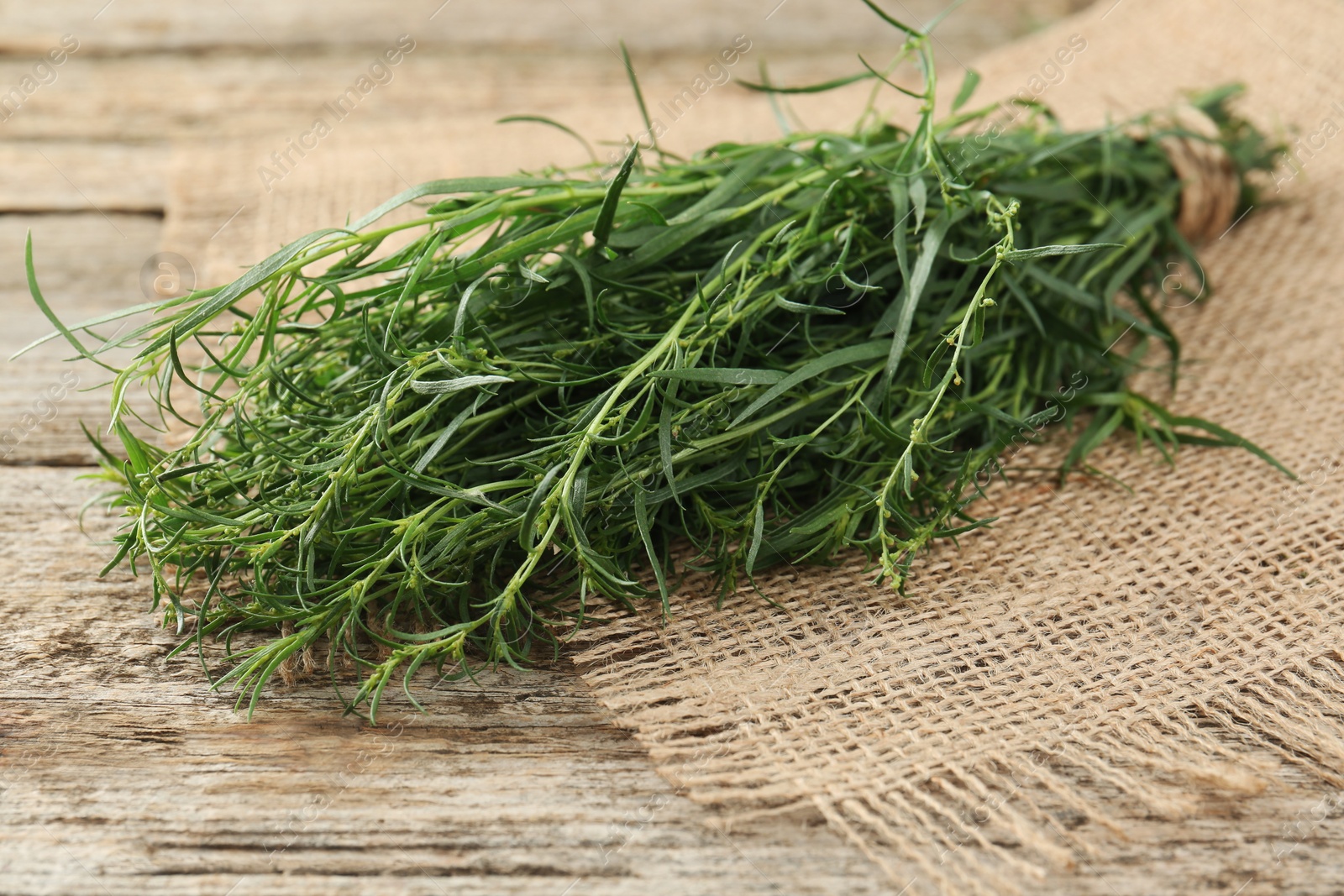 Photo of Bunch of fresh tarragon on wooden table, closeup