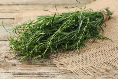 Photo of Bunch of fresh tarragon on wooden table, closeup