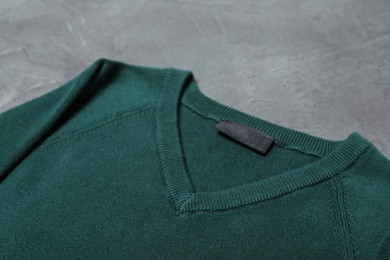 Photo of Green sweater on grey background, closeup. New stylish school uniform