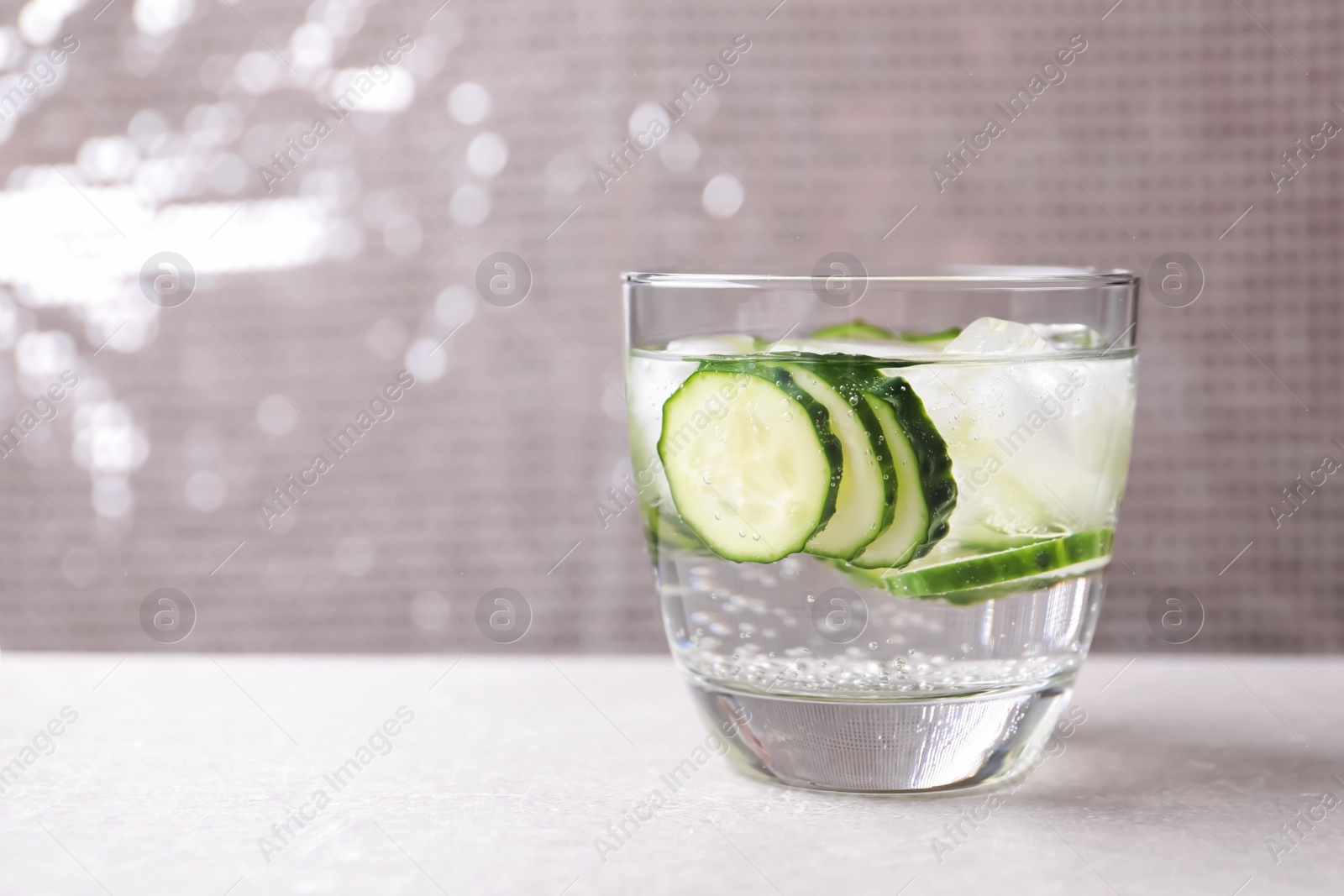 Photo of Glass of fresh cucumber water on table. Space for text