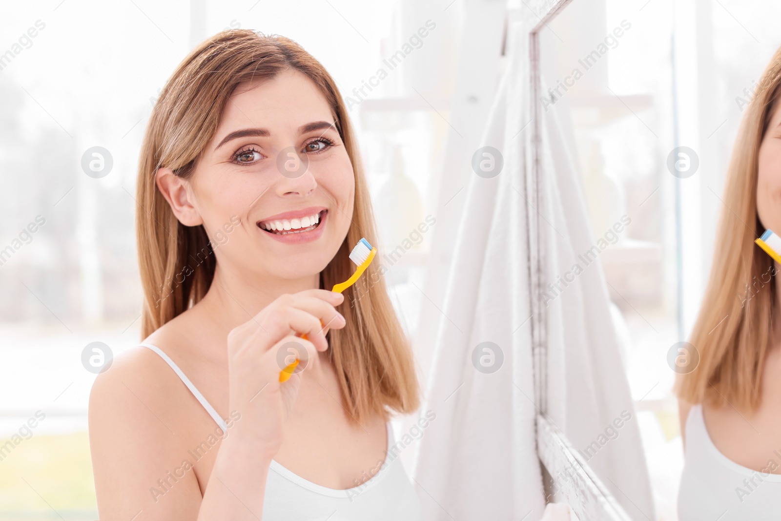 Photo of Young woman brushing her teeth in bathroom