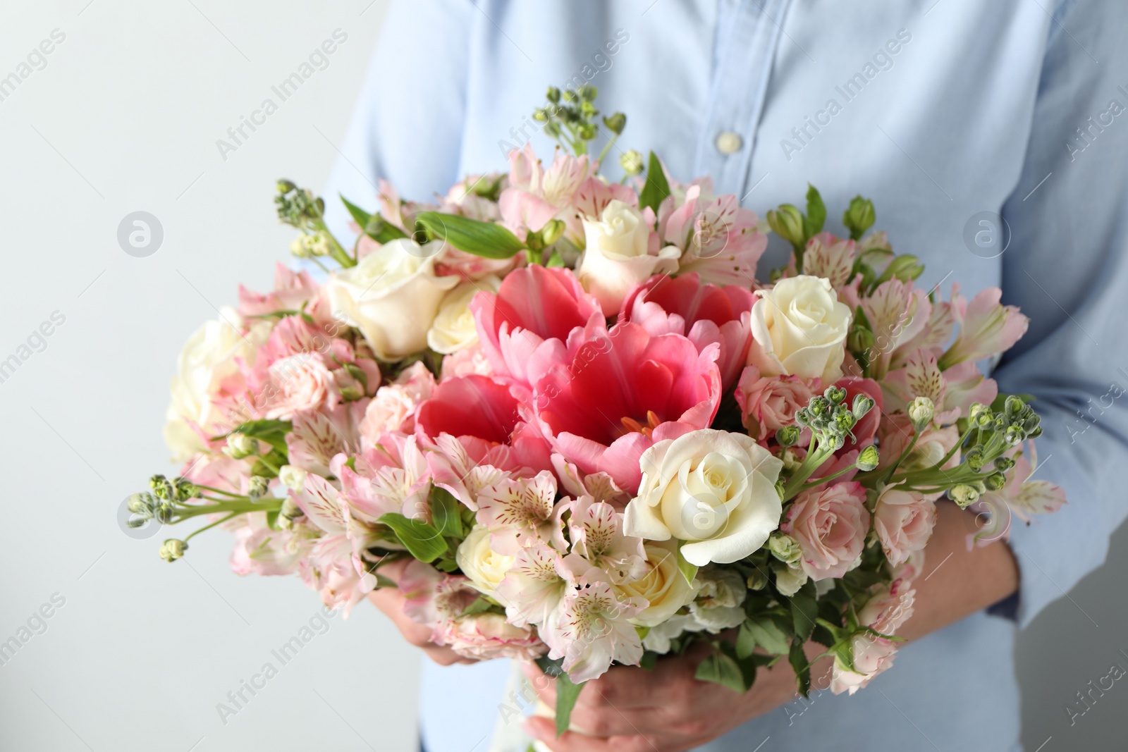 Photo of Woman with beautiful bouquet of fresh flowers on light background, closeup