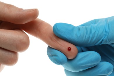 Doctor taking blood sample from patient's finger on white background, closeup