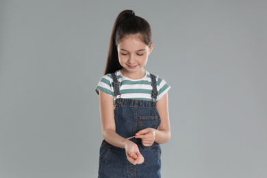 Photo of Girl putting sticking plaster onto wrist against light grey background