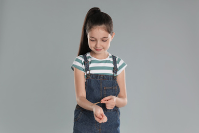 Girl putting sticking plaster onto wrist against light grey background