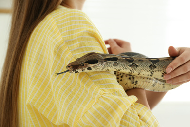 Photo of Young woman with boa constrictor at home, closeup. Exotic pet