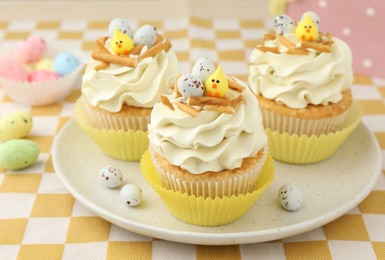 Photo of Tasty Easter cupcakes with vanilla cream on table, closeup