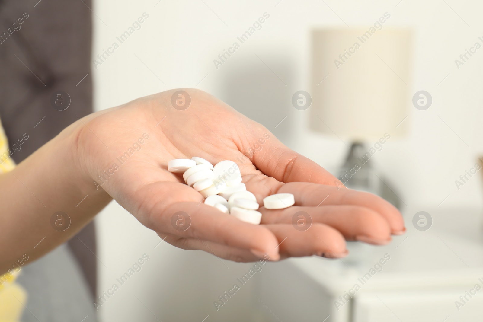 Photo of Woman holding many pills in hand indoors, closeup view