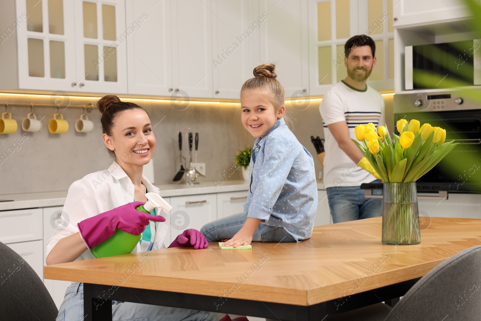 Photo of Spring cleaning. Parents with their daughter tidying up kitchen together