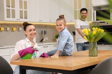 Photo of Spring cleaning. Parents with their daughter tidying up kitchen together