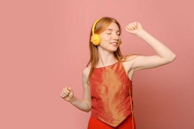 Photo of Portrait of beautiful young woman with headphones on pink background, space for text