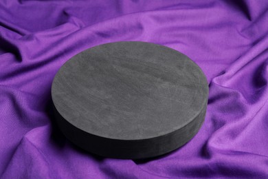 Photo of Black round stand on purple fabric, closeup. Stylish presentation for product