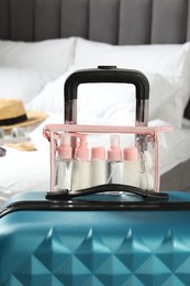 Cosmetic travel kit. Plastic bag with small containers of personal care products on suitcase in bedroom