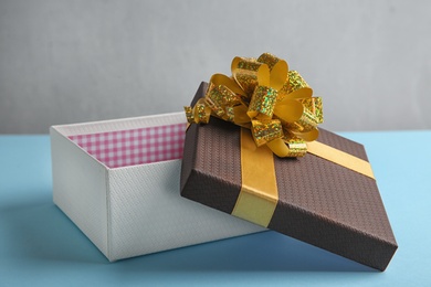 Photo of Beautiful open gift box on blue table