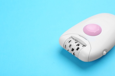 Photo of Modern epilator on blue background. Space for text